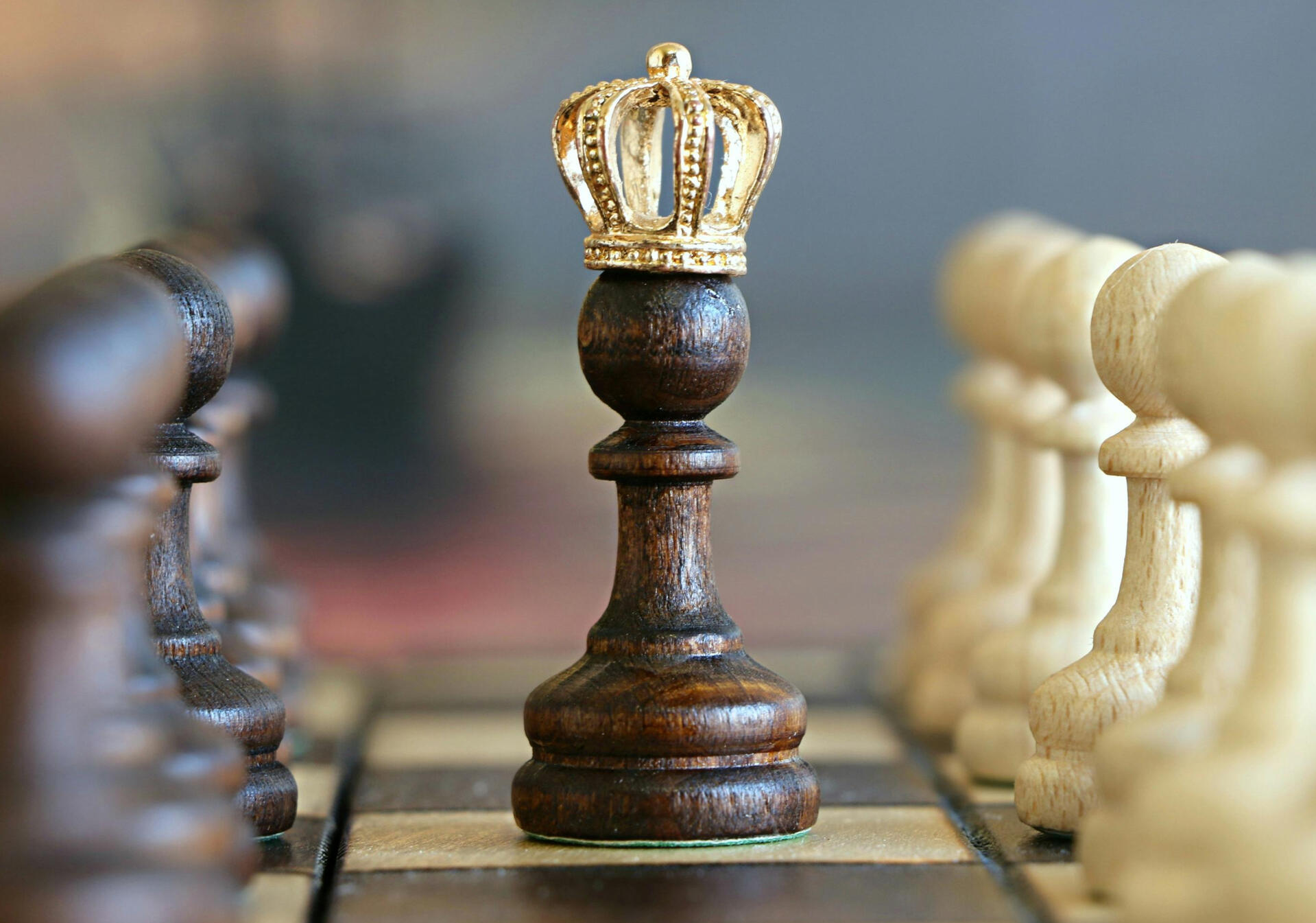 A chess pawn wearing a gold crown on a chessboard